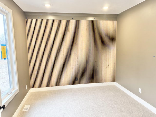 empty room featuring plenty of natural light, visible vents, baseboards, and carpet flooring