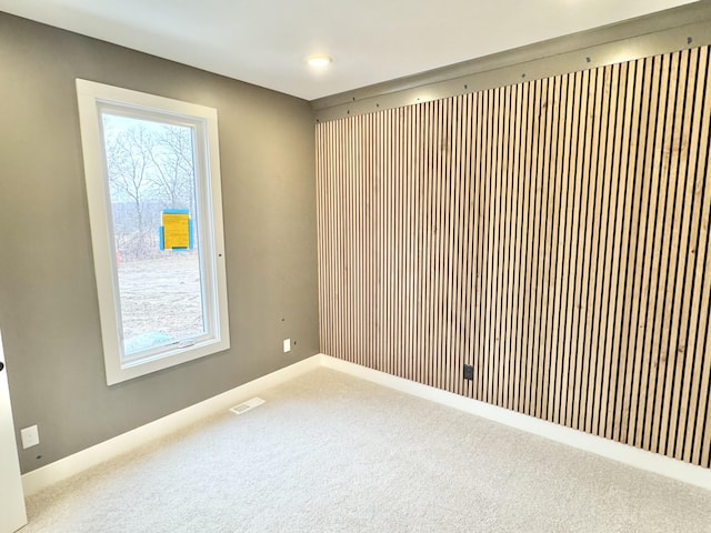 unfurnished room featuring carpet flooring, visible vents, and baseboards