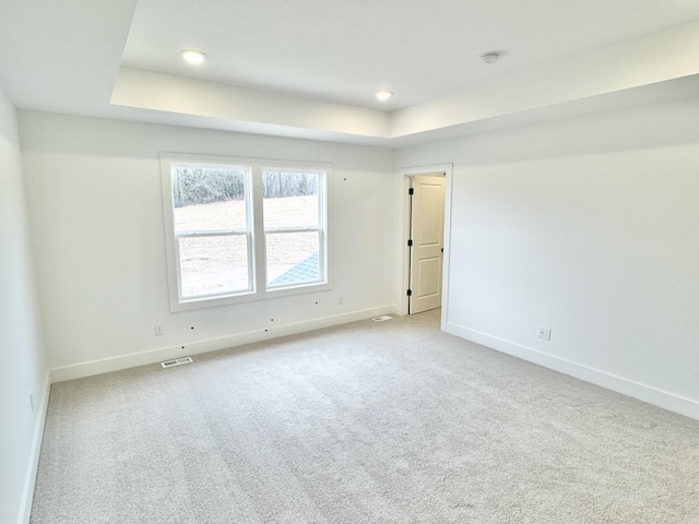 carpeted empty room with recessed lighting, a raised ceiling, visible vents, and baseboards