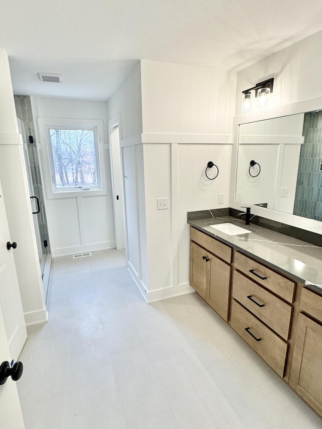 bathroom with a shower stall, visible vents, a decorative wall, and vanity