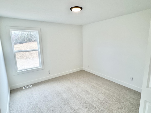 unfurnished room with carpet, visible vents, and baseboards