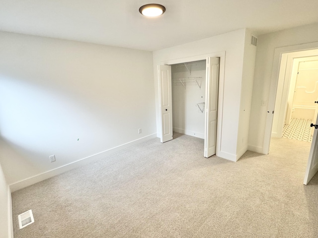 unfurnished bedroom with baseboards, a closet, and light colored carpet