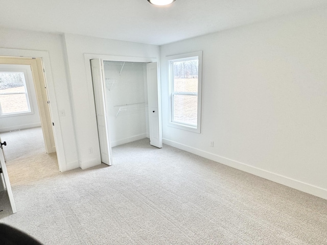 unfurnished bedroom featuring light colored carpet, baseboards, and multiple windows