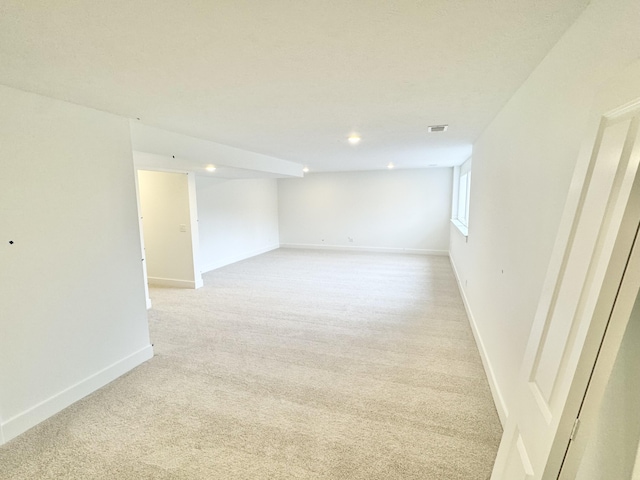 basement featuring light colored carpet and baseboards