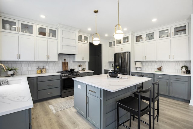 7711 96th St SE, Alto, MI 49302 - kitchen with stainless steel appliances, gray cabinets, a center island, tasteful backsplash, and white cabinets