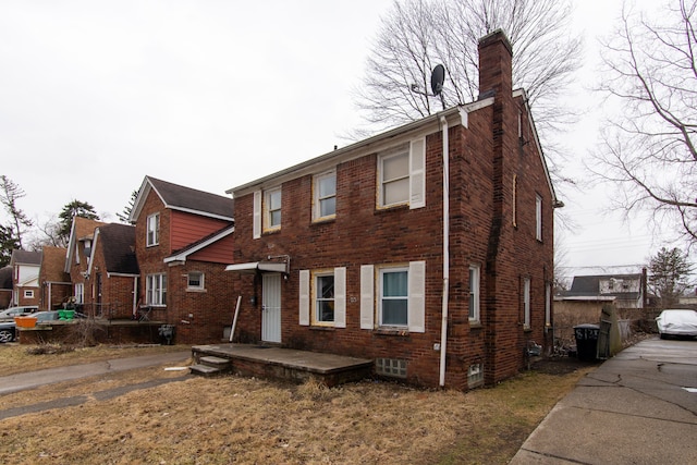 view of front of property with a chimney and brick siding