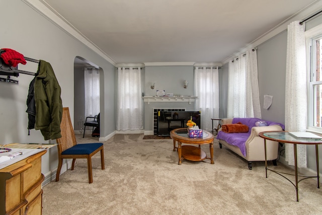 sitting room with arched walkways, baseboards, light colored carpet, a fireplace with flush hearth, and ornamental molding