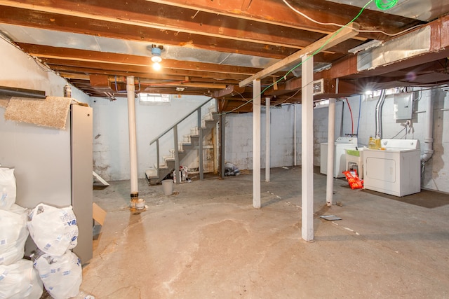 unfinished basement featuring electric panel, stairway, and washer and clothes dryer