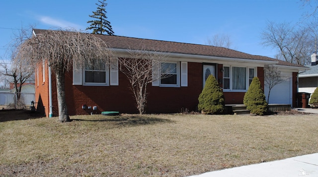 view of front of house with brick siding, an attached garage, a front lawn, and fence