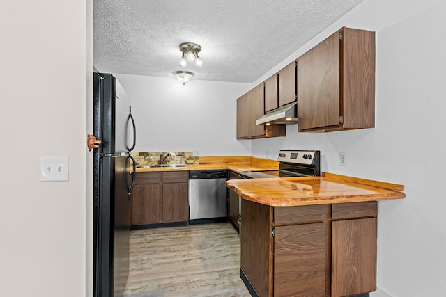 kitchen with light wood-style flooring, stainless steel appliances, light countertops, under cabinet range hood, and a sink