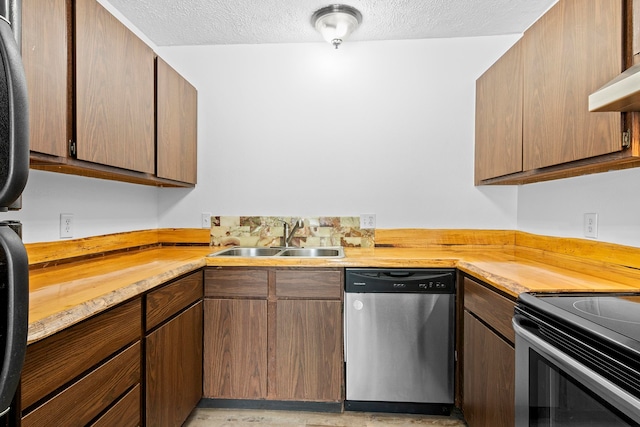 kitchen with under cabinet range hood, a textured ceiling, appliances with stainless steel finishes, and a sink