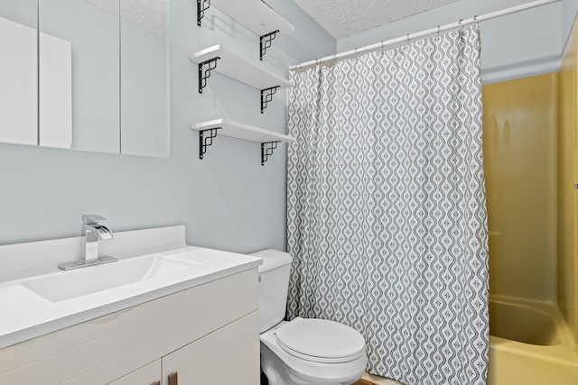 full bathroom with a textured ceiling, toilet, and vanity