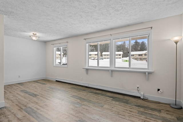 spare room featuring a textured ceiling, a baseboard radiator, wood finished floors, and baseboards