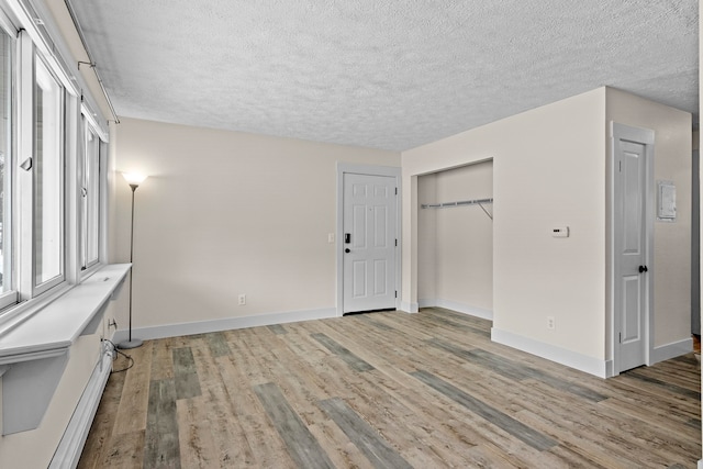 interior space featuring baseboards, a textured ceiling, and light wood-style floors