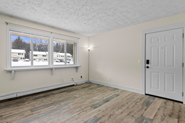 empty room with a textured ceiling, baseboards, baseboard heating, and wood finished floors