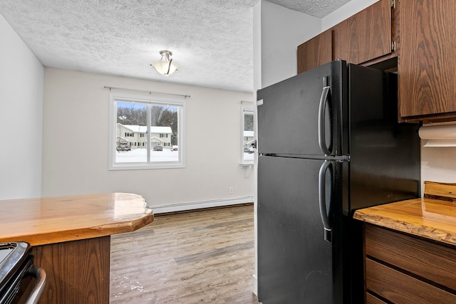 kitchen with a baseboard heating unit, butcher block counters, a textured ceiling, and freestanding refrigerator