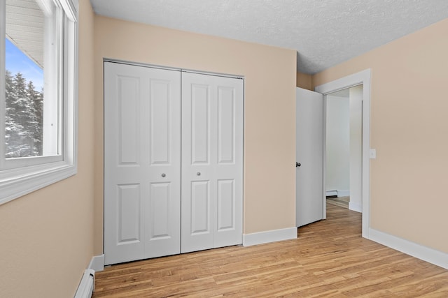 unfurnished bedroom with light wood finished floors, multiple windows, a closet, and baseboards