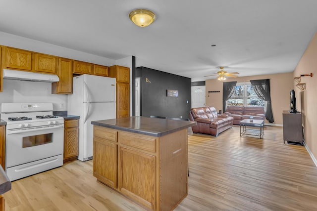 kitchen with white appliances, dark countertops, light wood-style floors, and under cabinet range hood