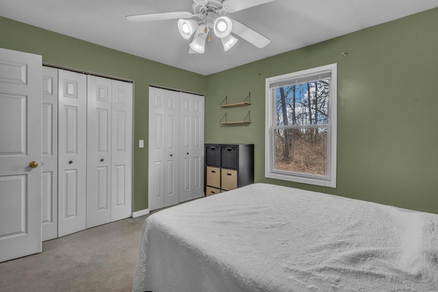 bedroom featuring carpet, a ceiling fan, and multiple closets