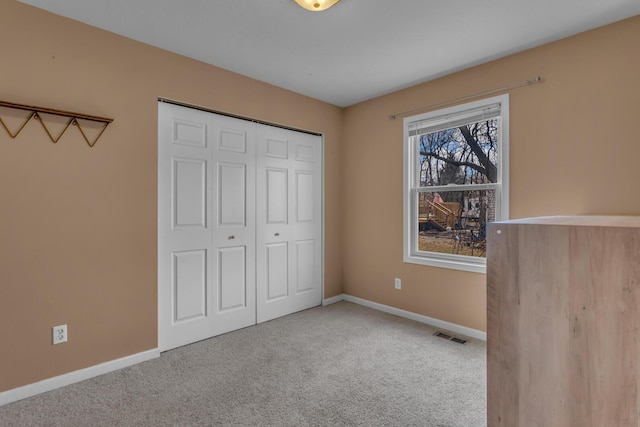 unfurnished bedroom with carpet, visible vents, baseboards, and a closet