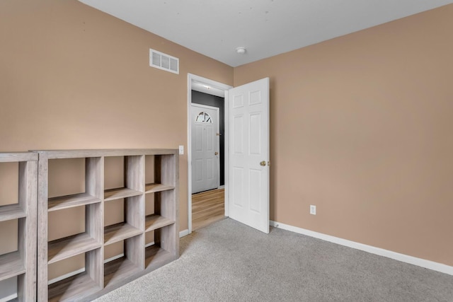 empty room featuring carpet, visible vents, and baseboards