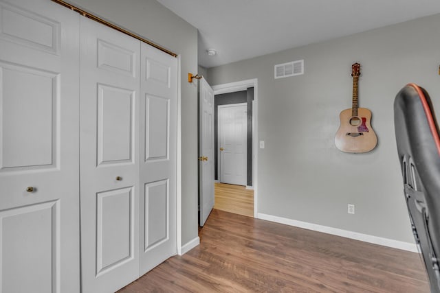 unfurnished bedroom featuring baseboards, visible vents, and wood finished floors