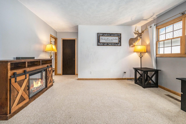 living area featuring a textured ceiling, carpet floors, visible vents, baseboards, and a glass covered fireplace