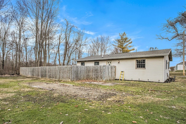 rear view of house featuring a yard and fence