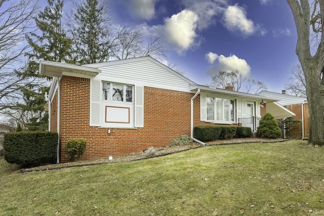 view of front of property featuring a front yard, a chimney, and brick siding