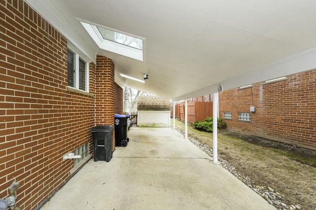 view of patio / terrace featuring driveway, fence, and an outbuilding