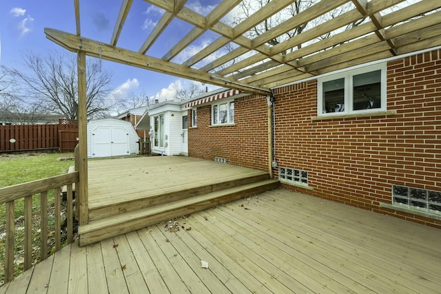 wooden terrace featuring a storage shed, an outbuilding, and fence