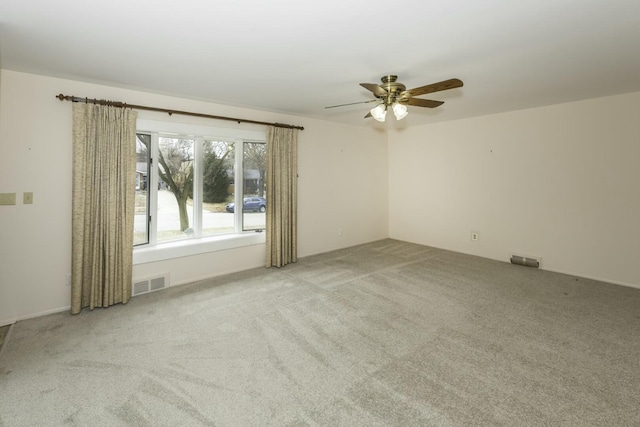 carpeted empty room with visible vents and ceiling fan