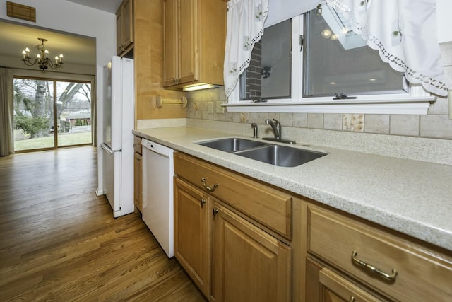 kitchen with white appliances, visible vents, brown cabinetry, light countertops, and a sink