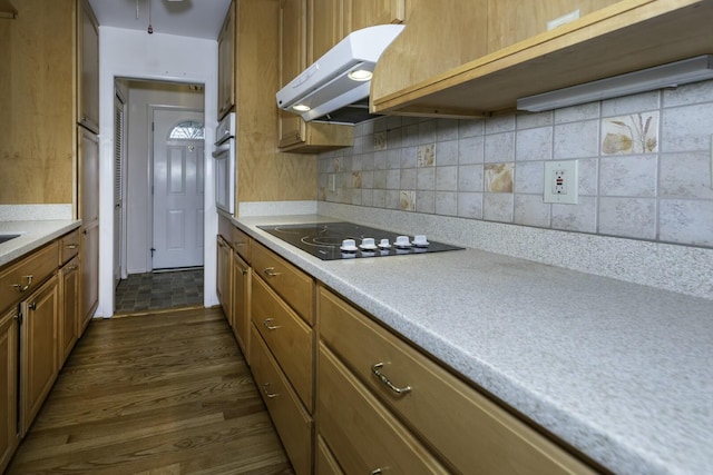 kitchen with dark wood-style floors, brown cabinets, black electric stovetop, light countertops, and exhaust hood