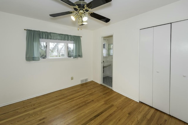 unfurnished bedroom featuring baseboards, visible vents, a ceiling fan, connected bathroom, and wood finished floors