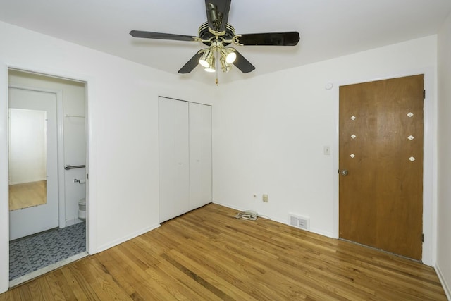 unfurnished bedroom with ceiling fan, visible vents, connected bathroom, and wood finished floors