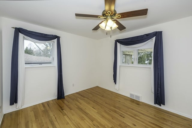 empty room featuring baseboards, light wood-type flooring, visible vents, and a healthy amount of sunlight