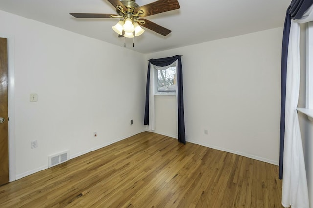 unfurnished room featuring ceiling fan, light wood-style flooring, visible vents, and baseboards