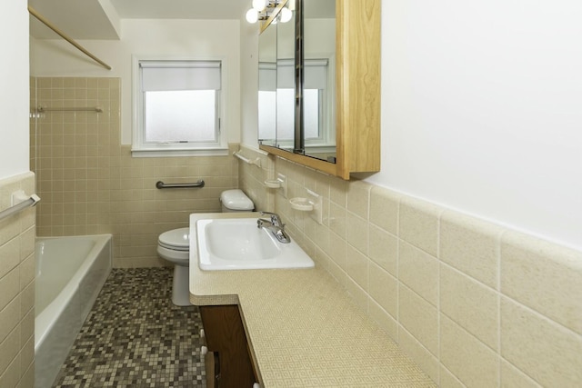 bathroom with shower / tub combination, toilet, vanity, tile walls, and wainscoting