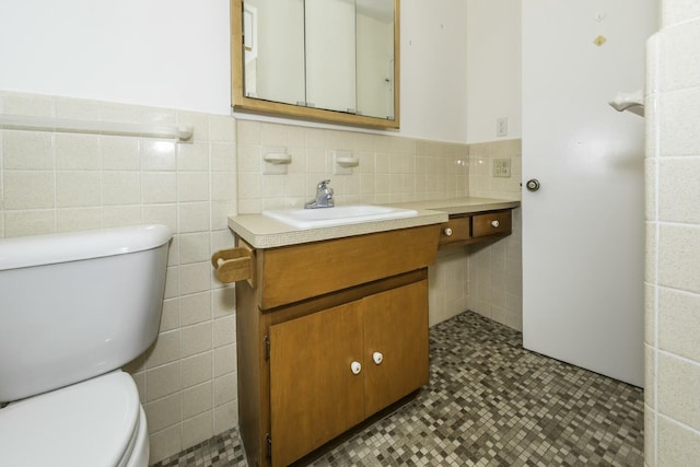 bathroom featuring toilet, wainscoting, tile walls, and vanity