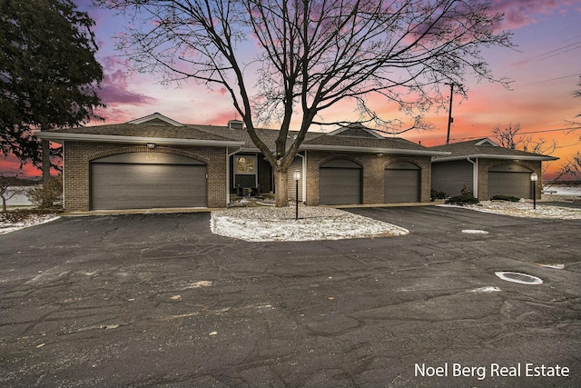 view of front of home with a garage, driveway, and brick siding