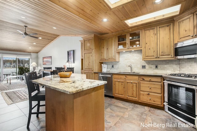 kitchen with a sink, wood ceiling, a kitchen breakfast bar, appliances with stainless steel finishes, and light stone countertops