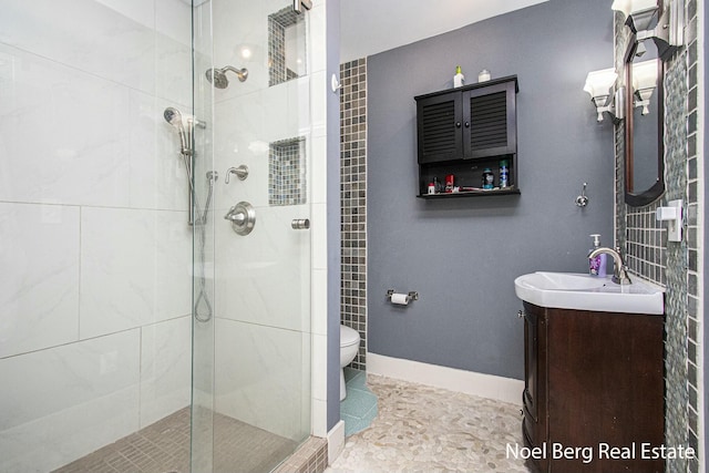 full bath with baseboards, toilet, a shower stall, and vanity
