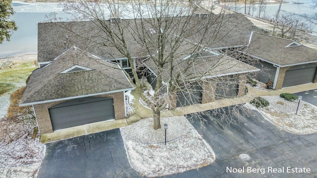 exterior space with a garage, driveway, a shingled roof, and brick siding