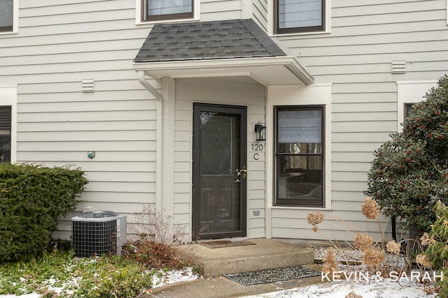 property entrance featuring roof with shingles and central AC