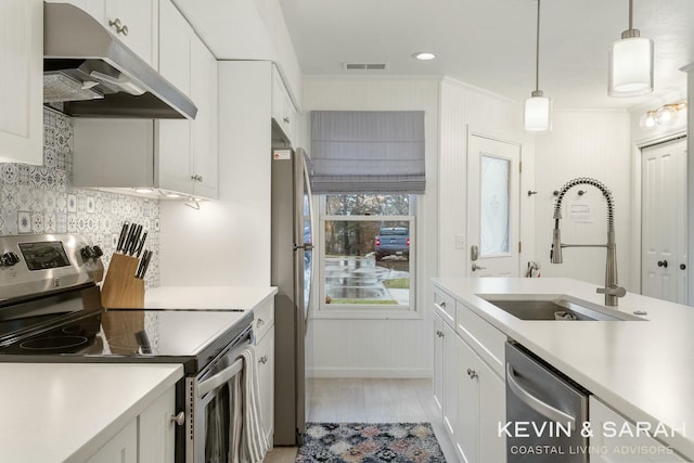 kitchen featuring under cabinet range hood, appliances with stainless steel finishes, white cabinets, and a sink