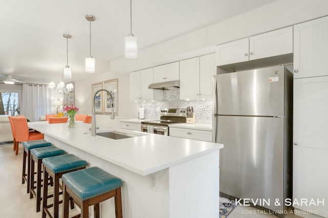 kitchen with under cabinet range hood, a sink, white cabinetry, appliances with stainless steel finishes, and backsplash