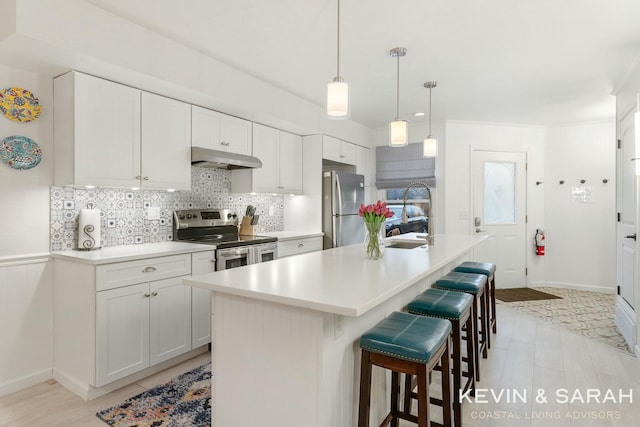 kitchen with tasteful backsplash, stainless steel appliances, light countertops, under cabinet range hood, and a sink