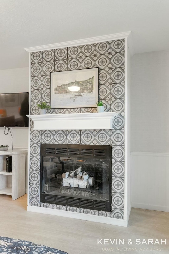 interior details with wainscoting, wood finished floors, and a glass covered fireplace