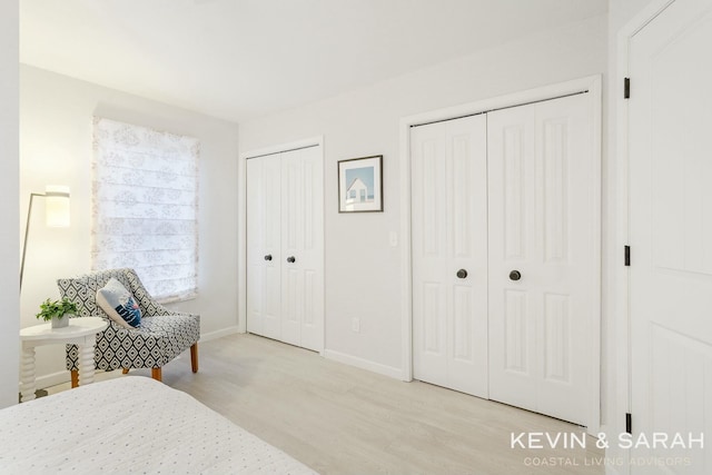 bedroom with wood finished floors, baseboards, and two closets